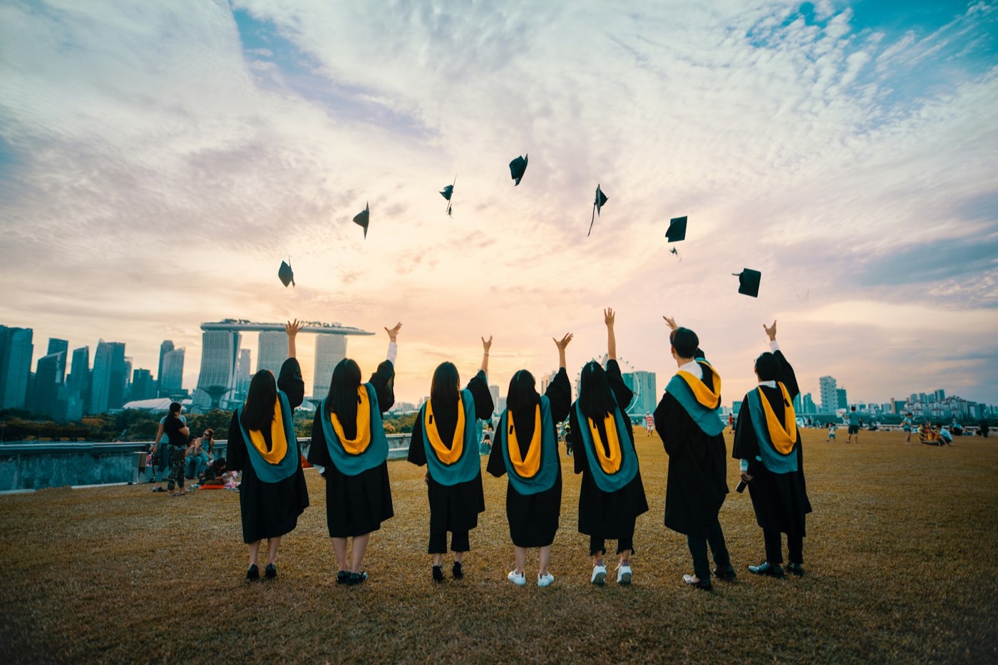 Graduates celebrating against a global financial-district skyline — the Allin journey from learner to leader